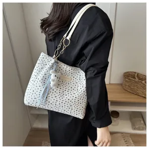 Detailaufnahme der geblümten Kord-Schultertasche mit Kettenriemen und Bärenanhänger.