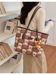 Vue détaillée du cabas imprimé ours marron avec poignées en cuir et joli pendentif en peluche.