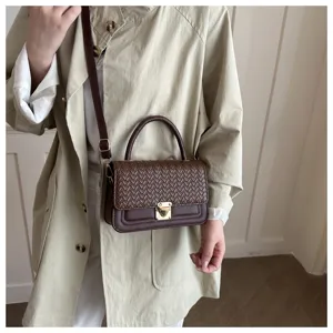 Detailansicht der braunen geflochtenen Ledertasche mit feiner Textur, Schloss und schönem Gurt.