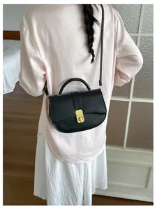Elegante borsa a sella nera da donna con chiusura in metallo, tracolla in pelle versatile.