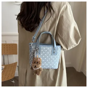 Detailansicht der Retro Pünktchen Mini Eimer Tasche in Hellblau mit süßem Plüschtier Anhänger.