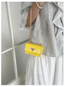 Gedetailleerd overzicht van een gele polka dot schoudertas met gouden ketting en slot.