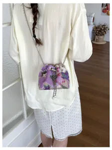 Detailaufnahme einer Damen Pailletten Blumen bestickten Umhaengetasche mit Kette und Perlen.