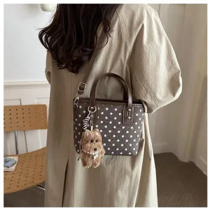 Detailansicht der Vintage Polka Dot Mini Eimer Tasche mit Kontrastlederbesatz und Plüschanhänger.