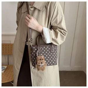 Detailansicht der retro braunen gepunkteten Mini-Handtasche mit süßem Bärenanhänger.