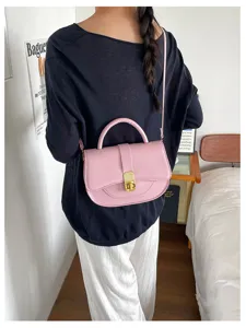 Primo piano della elegante borsa a sella rosa in pelle con chiusura metallica chic.