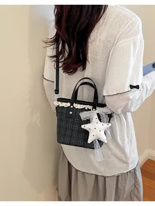 Detailed view of a classic plaid bucket bag featuring delicate lace trim and a cute star pendant.