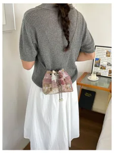 Detailansicht einer mit Pailletten und Blumen bestickten Beuteltasche mit feiner Kette.
