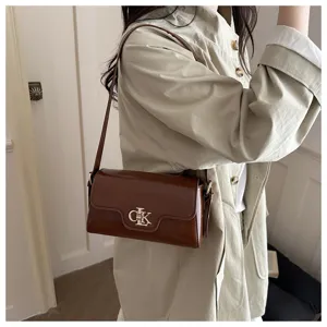 Vue détaillée du sac à bandoulière marron vintage avec fermoir en métal porté avec trench.