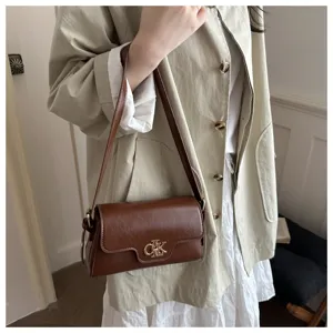 Vue détaillée d'un sac à main rétro en cuir marron avec fermoir métallique élégant, look chic.