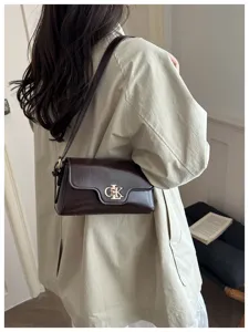 Vue détaillée d'un sac porté épaule marron rétro avec fermoir métallique et trench.