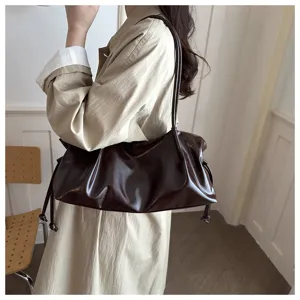 Detailed view of dark brown glossy leather shoulder bag showcasing soft slouchy texture.