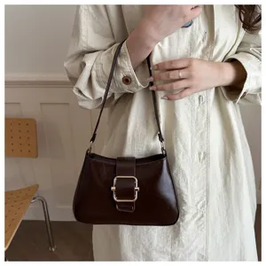 Dettaglio della borsa a spalla marrone retrò in pelle lucida con elegante fibbia in metallo.