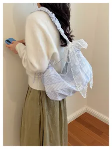 Detailed view of sweet blue striped canvas shoulder bag with delicate white lace and cute bows.