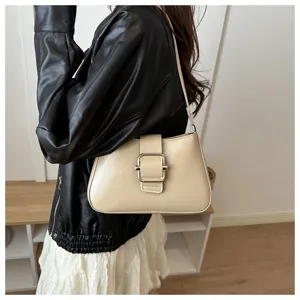 Dettaglio di una borsa a spalla beige chic con fibbia in metallo e tracolla sottile.