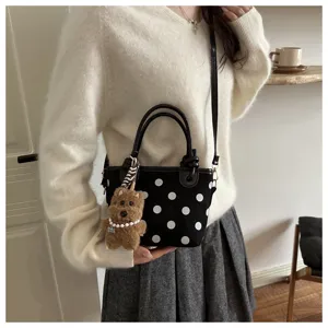 Sac seau chic à pois noirs avec pendentif en peluche, sac bandoulière tendance pour femmes.