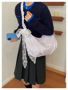 Detailed view of casual striped canvas shoulder bag with elegant lace bow and pleated strap.