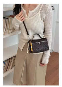 Dark brown woven crossbody box bag detail, featuring unique bead charms and smooth zipper.