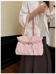 Dettaglio borsa a tracolla arricciata a pois rosa, pelle morbida, design tote semplice.
