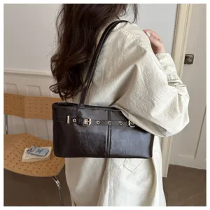 Detail view of a chic dark brown leather underarm shoulder bag with metal buckle strap.