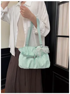 Detailed view of a light green polka dot shoulder bag with bow and pleats for women.