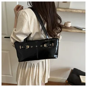 Detail view of a black patent leather shoulder bag with chic buckle straps for women.