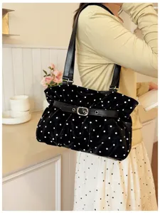 Primo piano della borsa a spalla plissettata a pois neri in morbida pelle con fibbia chic.