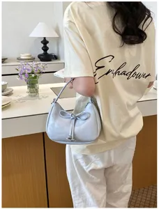 Modische hellblaue Schultertasche Dumpling Bag mit schicker Schleife und weichem Lederdesign.
