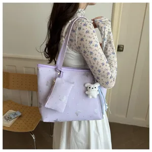 Vista dettagliata della borsa tote viola chiaro di tendenza con stampa farfalla e ciondolo.