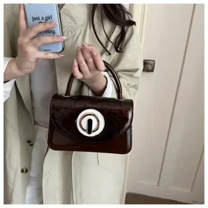 Bolso de mano de charol marron con hebilla redonda unica, bolso elegante para mujer chic.