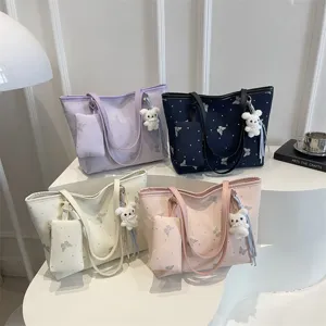 Vista dettagliata di borse tote alla moda in quattro colori con ciondoli a coniglietto e farfalle.