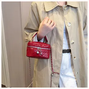 Gros plan détail d'un mini sac boîte matelassé rouge avec chaîne et charm cœur.