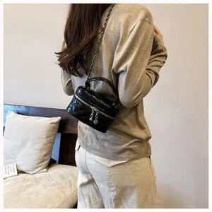 Vue detaillee du sac vanity noir matelasse a chaine avec poignee et pendentif coeur.