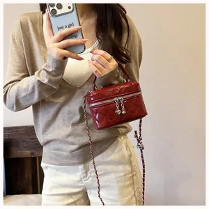 Gros plan détaillé d'un sac boîte matelassé rouge avec bandoulière chaîne et charm cœur.