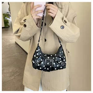 Vista detallada del elegante bolso de hombro negro para mujer de lunares con hebilla elegante.