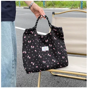 Black quilted tote bag featuring pink floral print and casual shoulder design detail.