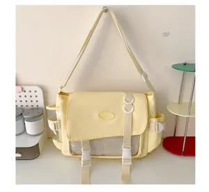 Canvas messenger bag detail showing front mesh pocket, dual buckles, and soft yellow color.