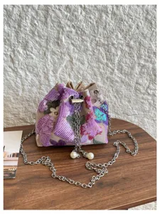 Detailansicht der lila floralen Pailletten-Beuteltasche mit Metallkette und Perlen.