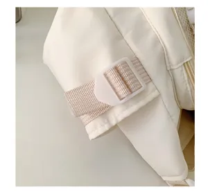 Close-up detail of the adjustable strap and white plastic buckle on the canvas messenger bag.