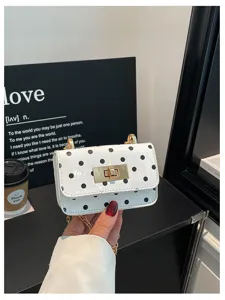 Elegante witte crossbody tas met zwarte stippen, gouden ketting en chique draaisluiting.