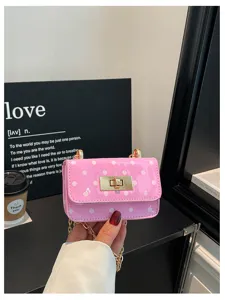 Roze polkadot crossbody tas detail, glanzend lakleer met gouden slot en kettingriem.