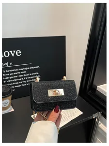 Gedetailleerd uitzicht op de stijlvolle zwarte glinsterende crossbodytas met goudketting slot.