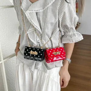 Stijlvolle damestas met polkadots, voorzien van een chique draaisluiting en goudkleurige ketting.