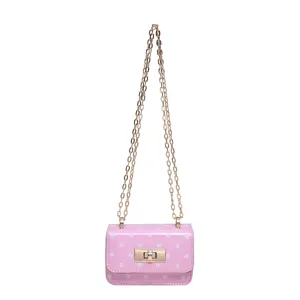Chique roze schoudertas met witte stippen, gouden kettingriem en metalen draaisluiting.