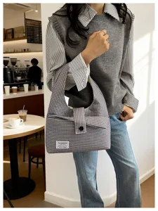 Detail view of a casual grey plaid shoulder bag, featuring minimalist commuter style and soft fabric.