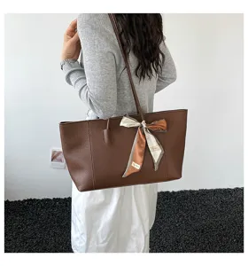 Dettaglio borsa shopper in pelle marrone con elegante foulard e pregiata texture.