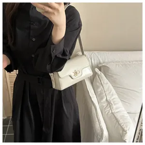 Vue détaillée de l'élégant sac à bandoulière blanc avec un fermoir métallique chic.