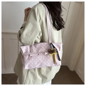 Vista di dettaglio ravvicinata della borsa tote rosa a pois con ciondolo a forma di orsetto.