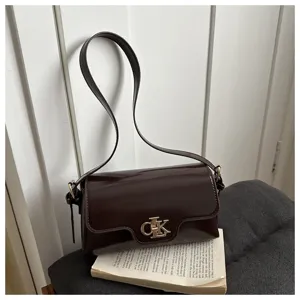 Sac à bandoulière rétro en cuir verni bordeaux foncé avec fermoir métallique élégant.