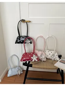 Gedetailleerd overzicht van de stijlvolle polkadot schoudertas met sterhanger en rits.